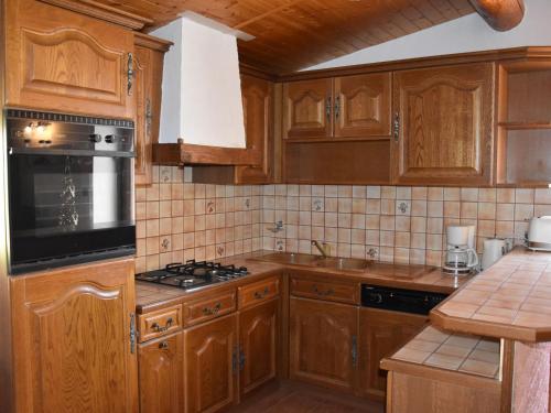 une cuisine avec des armoires en bois et un four à plaques de cuisson dans l'établissement Duplex lumineux avec mezzanine, proche pistes et centre, balcon sud, garage inclus - FR-1-464-194, à Pralognan-la-Vanoise