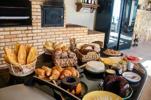 a table with various types of bread and pastries at Pousada dos Sonhos - MP in Miguel Pereira