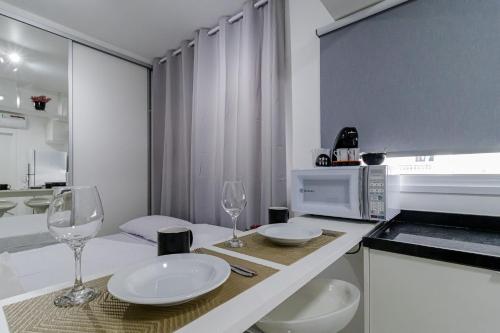 a kitchen with a table with two glasses and a microwave at Studios Modernos Totalmente Mobiliados com Academia Próximo a Metrô Parque Ibirapuera e Hospitais in Sao Paulo