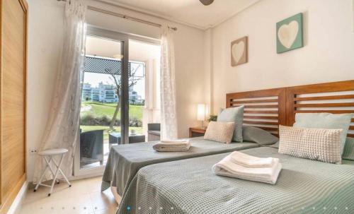 sypialnia z 2 łóżkami i dużym oknem w obiekcie Hacienda Riquelme Golf Resort Ground Floor Apartment w mieście Sucina