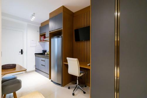 a kitchen with a desk and a stainless steel refrigerator at Studios Modernos Totalmente Mobiliados com Academia Próximo a Metrô Parque Ibirapuera e Hospitais in Sao Paulo