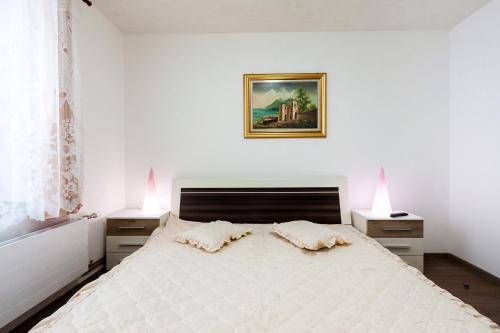 ein Schlafzimmer mit einem großen weißen Bett mit zwei Nachttischen in der Unterkunft Mónika Apartman in Remetea