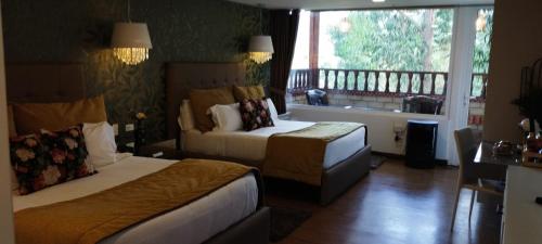 a hotel room with two beds and a balcony at Hotel Boutique Guatika in Tibasosa
