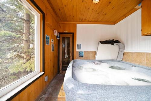 eine Badewanne in einem Zimmer mit Fenster in der Unterkunft Georgian Bay-Trail/Run/Bike/Hike/HotTub/Sauna/Swim in Waubaushene