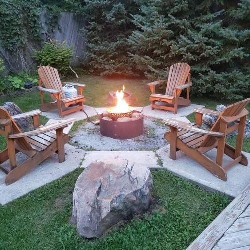 three chairs and a fire pit in a yard at Modern Chic Cottage - Hot Tub, Sauna, Tay Trail in Waubaushene
