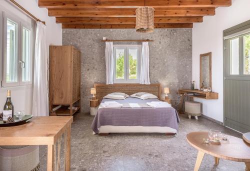 a bedroom with a bed and a table and windows at Sophia's Ralaki Cottage in Ralaki