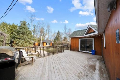 a large wooden deck next to a house at Modern Chic Cottage - Hot Tub, Sauna, Tay Trail in Waubaushene