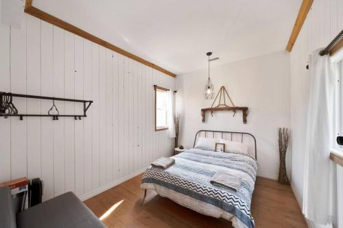 a bedroom with a bed in a room with white walls at Modern Chic Cottage - Hot Tub, Sauna, Tay Trail in Waubaushene