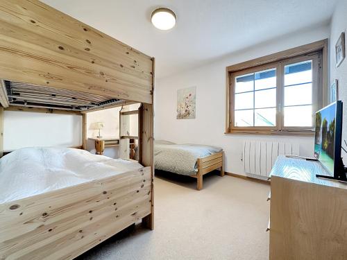 ein Schlafzimmer mit einem Etagenbett aus Holz und einem TV in der Unterkunft Our little marmots' dream in Bruson