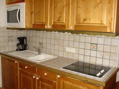 un comptoir de cuisine avec un évier et un micro-ondes dans l'établissement Rez-de-jardin cosy avec 3 pièces, proche pistes et centre de Pralognan-la-Vanoise - FR-1-464-55, à Pralognan-la-Vanoise
