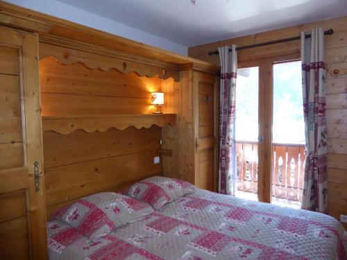 une chambre avec un lit et un mur en bois dans l'établissement Appartement Familial - Terrasse Sud, Parking, Proche Pistes - FR-1-464-59, à Pralognan-la-Vanoise