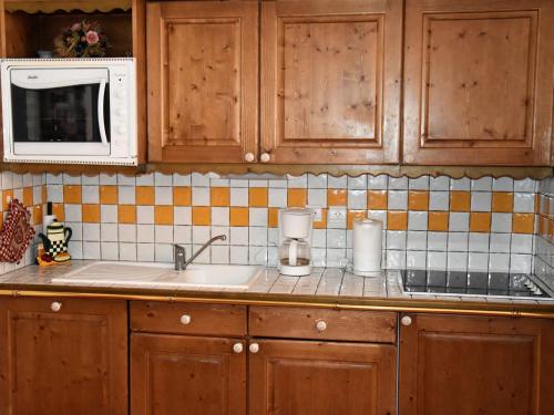 un comptoir de cuisine avec un évier et un micro-ondes dans l'établissement Appartement 3 pièces avec terrasse près des pistes - FR-1-464-63, à Pralognan-la-Vanoise
