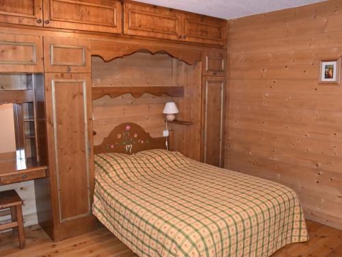 une chambre avec un lit dans une pièce aux murs en bois dans l'établissement Appartement lumineux avec terrasse, proche pistes et centre, idéal pour familles et PMR - FR-1-464-85, à Pralognan-la-Vanoise