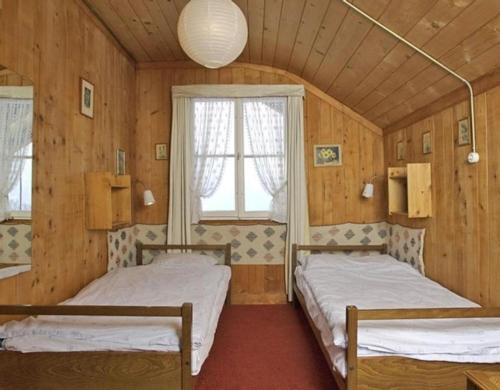 two beds in a room with wooden walls at Alpidyll Traditionelles 4 -Zimmer-Einzelchalet in Hasliberg