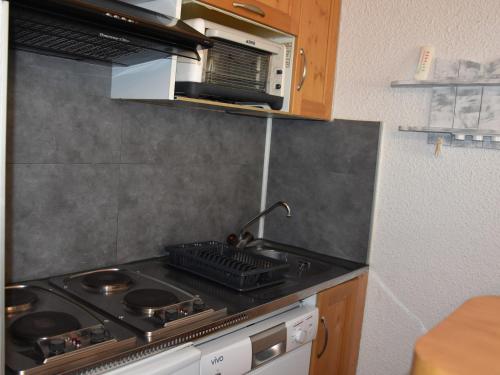 une cuisine avec une cuisinière et un micro-ondes dans l'établissement Appartement central avec balcon, proche commerces et téléphérique, parking privé, 4 personnes - FR-1-464-104, à Pralognan-la-Vanoise