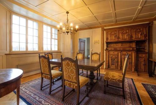 una sala da pranzo con tavolo, sedie e lampadario pendente di Ferienwohnung Schloss Heidegg a Gelfingen