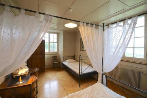 a bedroom with two beds and two windows at Ferienwohnung Schloss Heidegg in Gelfingen