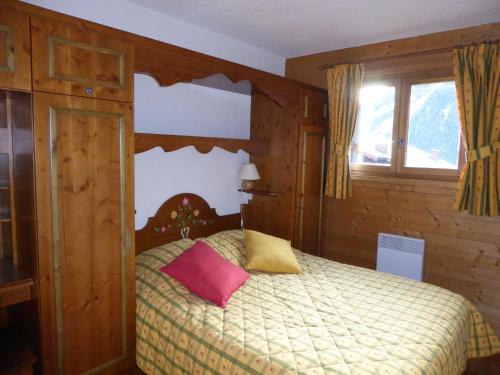 プラローニャン・ラ・ヴァノワーズにあるAppartement Pralognan-la-Vanoise, 3 pièces, 4 personnes - FR-1-464-114のベッドルーム1室(ピンクと黄色の枕が付いたベッド1台付)