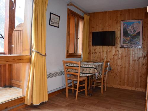 une salle à manger avec une table, des chaises et une télévision dans l'établissement Studio charmant au centre, proche commerces et téléphérique - FR-1-464-122, à Pralognan-la-Vanoise