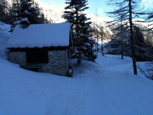 a building covered in snow with trees and mountains at Rustico Bersacola in Bosco Gurin