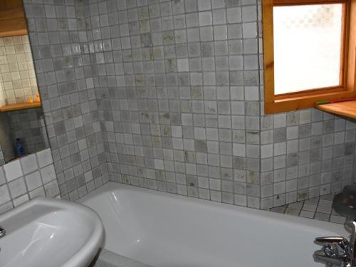 une salle de bain avec une baignoire blanche et un lavabo dans l'établissement Charmant Appartement au Centre de Pralognan, Proche Téléphérique et Commerces - FR-1-464-132, à Pralognan-la-Vanoise