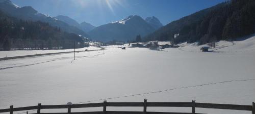 a snow covered field with a fence and mountains at Ferienhaus Widmann in Kirchberg in Tirol