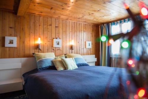 a bedroom with a blue bed with wooden walls at Hasliberg Goldern - traditionell und modern in Hasliberg