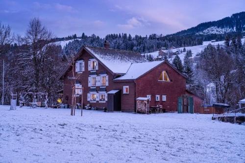 a large red barn in a snow covered field at Studio Chic mit Whirlpool in Wildhaus