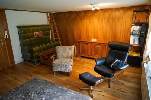 ein Wohnzimmer mit 2 Stühlen und einem Schreibtisch in der Unterkunft 4-Bett- Ferienwohnung Brachli in Innertkirchen