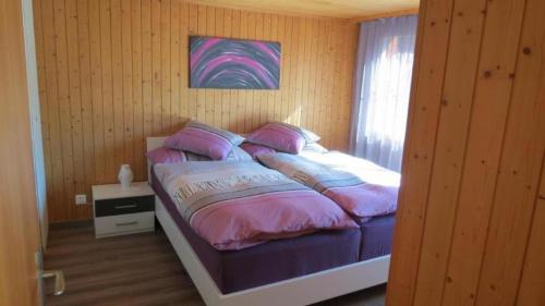 um quarto com uma cama com almofadas rosas e roxas em Ursula und Daniel 6-Bettwohnung Meiringen em Meiringen