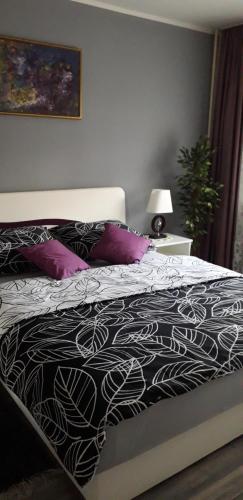 a bed with a black and white comforter and purple pillows at APARTMAN PARK in Šabac