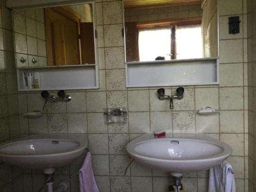 La salle de bains est pourvue de 2 lavabos, d'un miroir et d'une fenêtre. dans l'établissement Chalet mit grossem Umschwung, à Cerniat