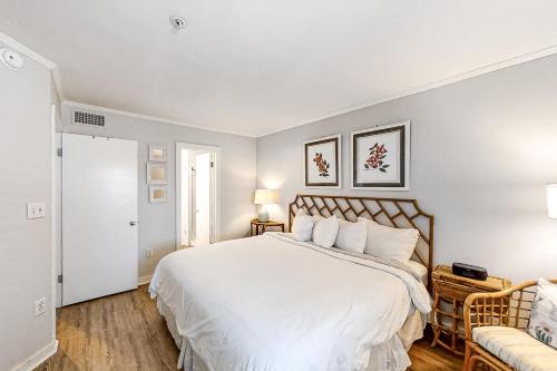 a white bedroom with a large bed and a chair at Beach Trees Lodge in Myrtle Beach