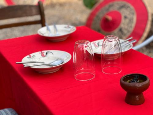 a red table with plates and glasses on a red table cloth at กิ่วลม - ชมลคอร Kiwlom - Chomlakorn, Lampang, TH in Lampang