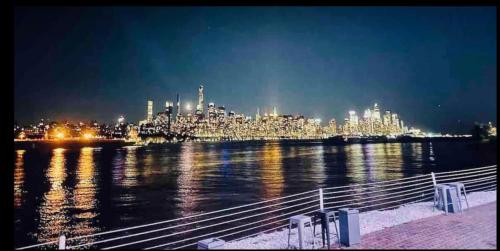 a view of a city from the water at night at Cozy Apartments close to New York City in North Bergen
