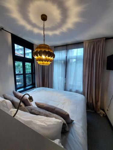 a bedroom with a large white bed and a chandelier at Saya Boutique Hotel in Amersfoort