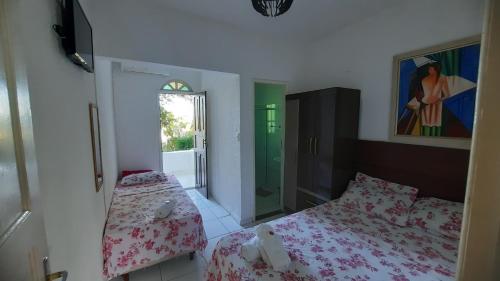Pousada Casa Verde في غواراباري: غرفة نوم صغيرة بسريرين ونافذة