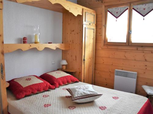 une chambre avec un lit avec des oreillers rouges dans l'établissement Charmant appartement proche des pistes, balcon, animaux admis - FR-1-464-6, à Pralognan-la-Vanoise