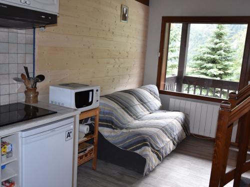 une petite cuisine avec un canapé et une fenêtre dans l'établissement Charmant appart avec mezzanine, balcon sud, piscine chauffée, proche pistes et centre - FR-1-464-5, à Pralognan-la-Vanoise