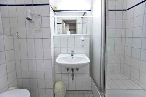 a white bathroom with a sink and a toilet at Leine-Hotel in Göttingen