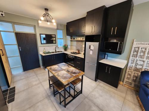 a kitchen with black cabinets and a table in it at Escape to 203 Umdloti Holiday Resort in Umdloti
