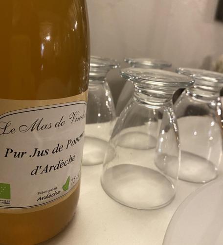 a bottle of wine sitting next to two empty glasses at Logis Hôtel Médiéval, Montélimar Nord in Rochemaure