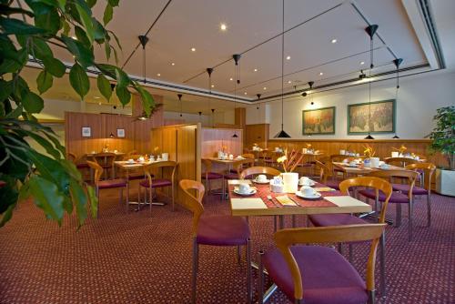 a restaurant with wooden tables and purple chairs at Leine-Hotel in Göttingen