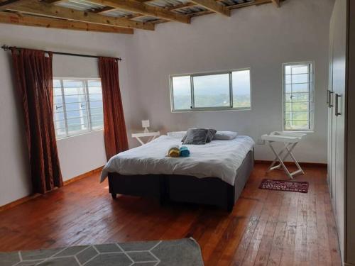 1 dormitorio con 1 cama grande en una habitación con ventanas en Best view of 1000 Hills with shared pool., en Bothaʼs Hill
