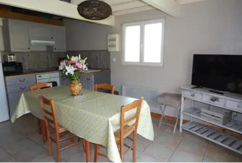 eine Küche mit einem Tisch mit Stühlen und einem TV in der Unterkunft Le bon coin en Baie de Somme in Boismont