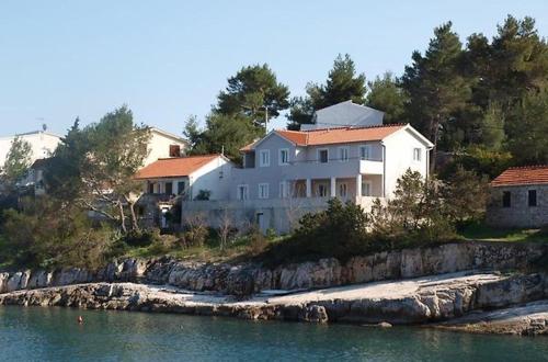 une grande maison blanche sur une colline à côté de l'eau dans l'établissement Hvar beach vacation, à Vrboska