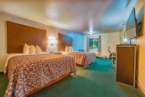 a hotel room with two beds and a flat screen tv at Turlock Inn in Turlock