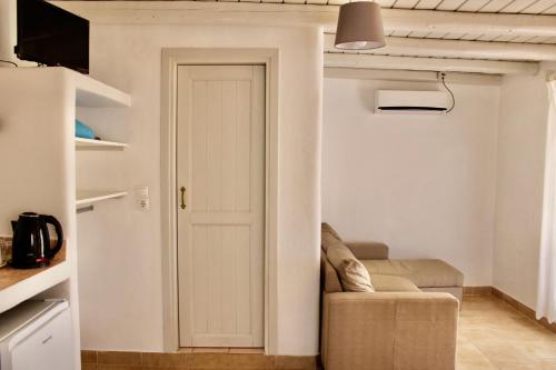 a living room with a door and a couch at Iliovasilema Studios Koufonisi in Koufonisia