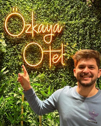 a man standing in front of a hedge with a sign at Özkaya hotel in Sivas