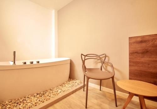 a bathroom with a tub and a chair and a table at Fence by Bernalo Hotels in Medellín